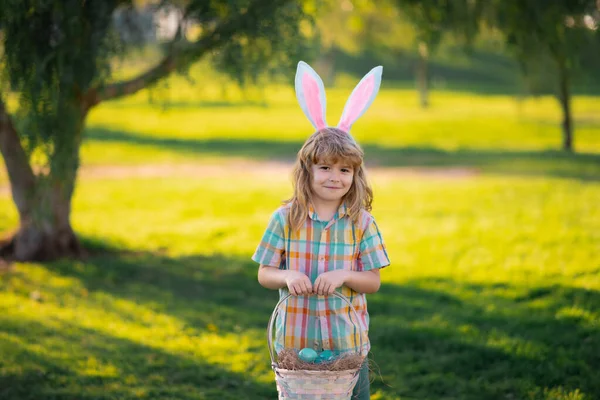 Barnpojke jagar påskägg. Söt unge i kanindräkt med kaninöron som har påsk i parken. Glad påsk. — Stockfoto