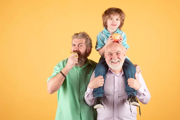 Abuelo padre y nieto abrazando y comiendo manzana. Hombres en diferentes edades. — Foto de Stock