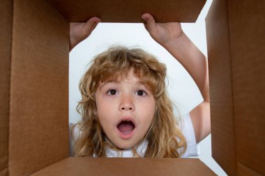 Heyecanlı çocuk kutuya bakıyor, karton kutu taşıyor. Çocuklar şaşırmış yüz ifadeleri.