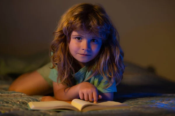 Дети читают книги. Ребенок читает книгу в постели перед сном. Ребенок читает книгу перед сном. Мальчик читает сказки на ночь. — стоковое фото