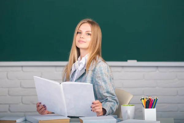 Portret młodej studentki trzymającej książkę studiującą w klasie na tle tablicy. — Zdjęcie stockowe