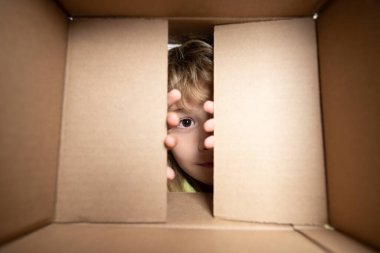 Karton kutulu mutlu çocuk, internet mağazasından paketleri açıyor. Çocuk müşteriler hızlı teslimat hizmetinden memnun. Kutusu açık bir çocuk. Gözlerini kapat ve bak..