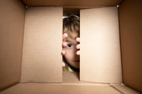Happy child with cardboard box, unpacking parcel from internet store. Kids client satisfied with fast delivery service. Child with open box. Close up eyes looking. — Stock Photo, Image