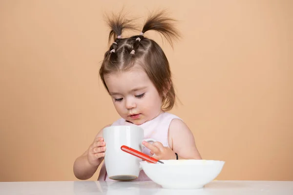 Leuke grappige baby 's die eten, babyvoeding, Babys eerste maaltijd. Het kind eet alleen met een kopje.. — Stockfoto
