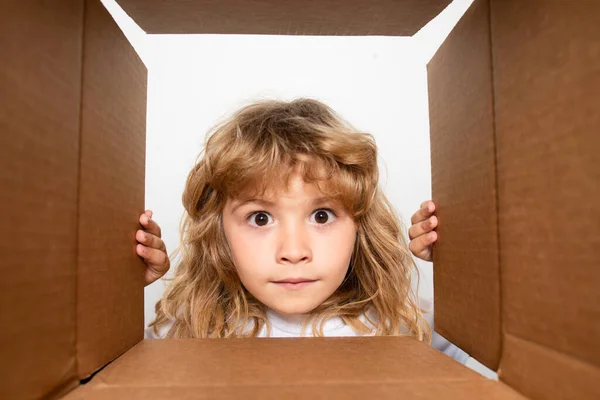 Enfant surpris déballer et ouvrir la boîte en carton, et regarder à l'intérieur avec le visage surprise. Parcelles, service de livraison. — Photo