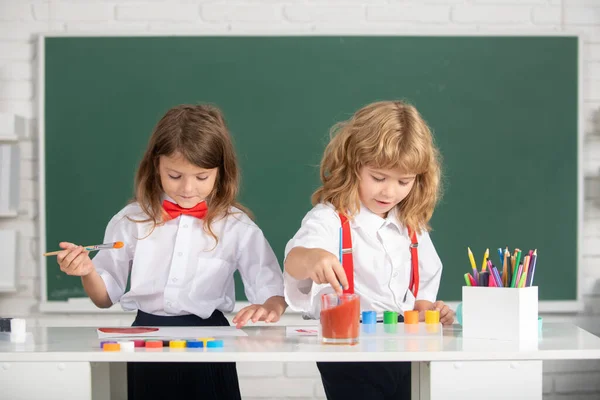 Små konstnärer målar, barn tecknar konst. Söta skolkamrater som tecknar och målar i skolan. Vänlig pojke en flicka roliga pupiller rita. Vänskap i skolan. — Stockfoto