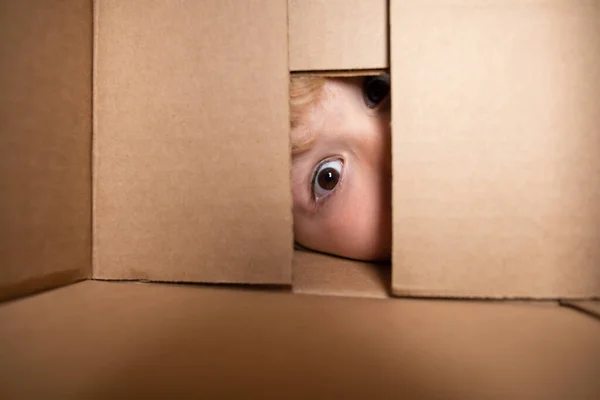 Dětská otevřená kartonová krabička, obal otevřená a uzavřená kartonová krabička. Zavři oči a podívej se. Chlapec vypadá překvapeně do dárku. — Stock fotografie