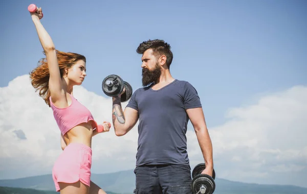 Pareja deportiva con mancuerna al aire libre. Un par de ejercicios con pesas. Hombre fuerte y mujer sexy haciendo ejercicio con pesas. —  Fotos de Stock