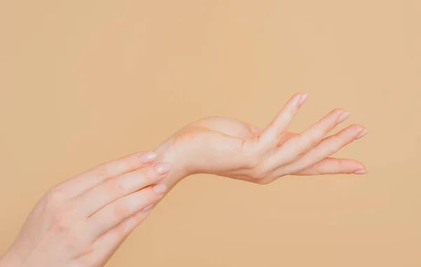 Cuidado com as mãos. Belas mulheres mãos no fundo bege. Belas mãos de mulher com nata. — Fotografia de Stock