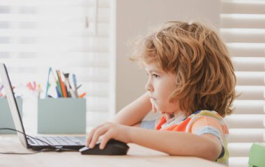 Ders sırasında dizüstü bilgisayara bakan okul çocuğunun portresi. Çocuk için eğitim ve öğrenim.