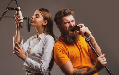 Kayıt stüdyosunda şarkı söyleyen adam ve genç kadın. Mikrofonlu etkileyici bir çift. Heyecanlı yüzlü mutlu arkadaşlar müziğin tadını çıkarın..