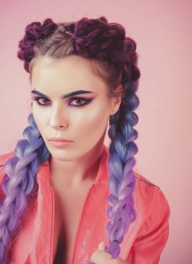Renkli makyaj ve örgülü saçlar. Sanat tasarımı olan muhteşem Avrupalı kadın modelin moda fotoğrafı. Gözler parlıyor. Pembe arka planda izole edilmiş, kameraya bakan seksi bir kızın stüdyo fotoğrafı..