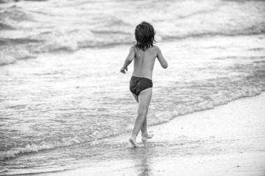 Tatlı çocuk yazın kumsalda koşuyor ve eğleniyor..