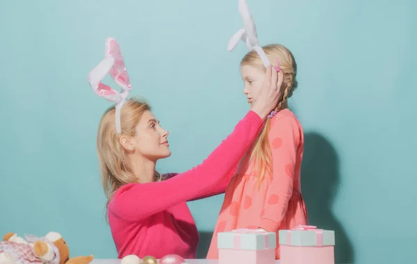 Szczęśliwa rodzina przygotowuje się do Wielkanocy. Matka i jej córka dziewczynka noszą królicze uszy odizolowane na niebiesko. — Zdjęcie stockowe