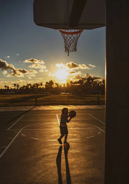 Söt leende pojke spelar basket. Aktiva barn njuter utomhus spel med korg boll. Sport för barn. — Stockfoto