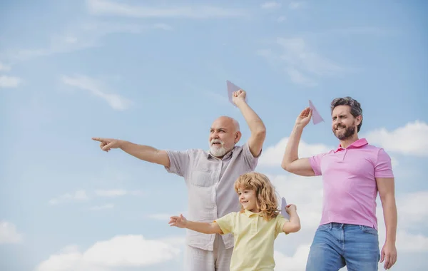Поколение мужчин: дед, отец и внук играют с игрушечным самолетом на открытом воздухе в небе. Мальчик мечтает стать пилотом. — стоковое фото