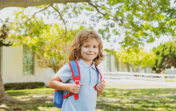 Dzieciak z plecakiem idzie do szkoły. Koncepcja edukacji dzieci. Dziecko z plecakami stojące w parku koło szkoły. Uczniowie z książkami i plecakami na zewnątrz. — Zdjęcie stockowe