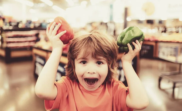 Söta småbarn pojke i en mataffär eller en stormarknad väljer färska ekologiska morötter. Hälsosam livsstil för ung familj med barn — Stockfoto