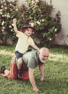 Babalar günü. Büyükbaba dışarıda oynarken mutlu çocuk. Babalar günü. İki farklı nesil yaş: büyükbaba ve torunu birlikte. Baba ve büyükbaba.