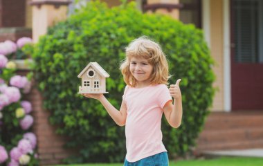 Elinde oyuncak evleri olan bir çocuk. İpotek, ev sigortası, gelecek planları, çocukları koruma..