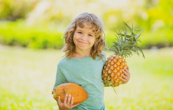 Çocuk elinde ananas ve hindistan cevizi tutarak gülümsüyor. Yaz meyveleri. — Stok fotoğraf