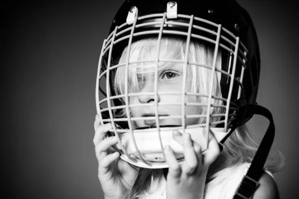 Lány aranyos gyermek viselni Jégkorong sisak közelről. Biztonság és védelem. Védőháló az arcon. Sportfelszerelés. Jégkorong vagy rögbi sisak. A sport gyermekkori. Jövő sportsztár. Sport neveltetés és karrier — Stock Fotó