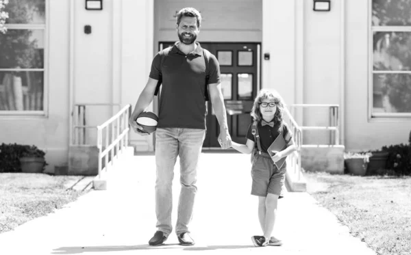 Padre caminando hijo a la escuela. Padres y alumnos de escuela primaria con mochila. — Foto de Stock