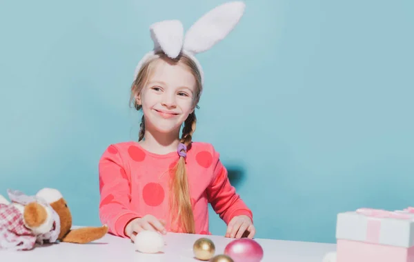 Милый маленький ребенок с кроличьими ушами на Пасху. Улыбающаяся девушка держит корзину с окрашенными яйцами. — стоковое фото