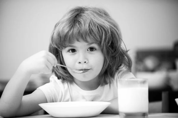 Närbild ansikte unge äta ekologisk mat, yoghurt, mjölk. Barnet äter hälsosamt. Leende liten pojke äter mat på köket. — Stockfoto