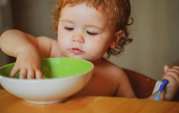 子供の赤ちゃんは料理とスプーンでキッチンでスープを食べる. — ストック写真