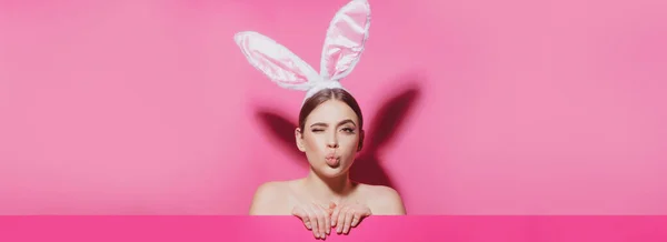 Pasen spandoek met konijnenvrouw. Close-up portret van aantrekkelijk vrolijk meisje met roze oren, luchtkus. Paashaas vrouw. — Stockfoto