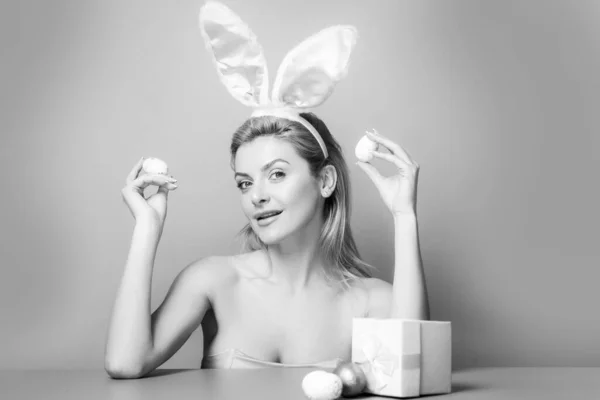 Mujer con orejas de conejo sostienen huevo de Pascua sobre fondo rosa. — Foto de Stock