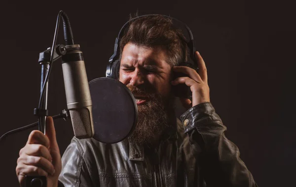 Mann mit Mikrofon singt Lied. Musiker im Musiksaal. Ausdrucksstarke Nahaufnahme. — Stockfoto