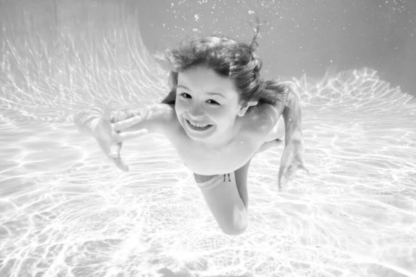 Kid boy swimming underwater. Kid in the water swimming under water and smiling. Child swim underwater in pool. Funny happy kids face. — Stock Photo, Image