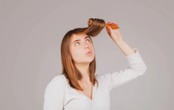 Retrato de una joven divertida peinándose el pelo, sonriendo. Cepillado femenino cabello sano con peine. —  Fotos de Stock
