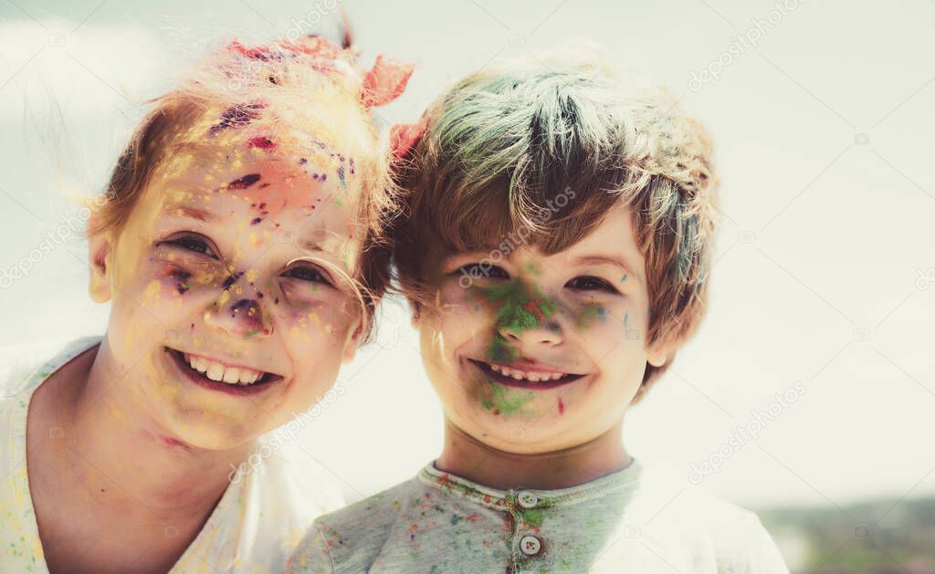 Smiling little kids portrait. Painted faces of funny kids. Children holi festival of colors. Little boy and girl plays with colors.