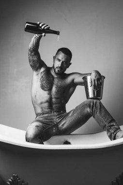 Lüks elit eğlence. Lüks hayatı şampanya şişesi ile kavramı. Acımasız adam, banyo içine dökülen şampanya ile. Lüks hayat. Lüks elit alkol ile çekici erkek.