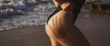 Denize geri dönen genç bayan sporcunun yakın çekimi. Eğitimli el izli kalçalar, formda..