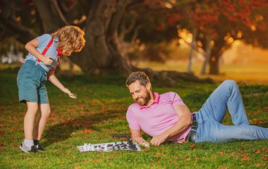 Baba oğul çim parkında çimlerde satranç oynuyorlar. Babalar Günü.