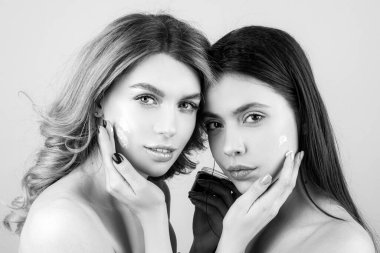 Yüz kilinden maske takan spa kadını. Yüz maskeli iki güzel kadın stüdyo arka planında eğleniyor. Yüz maskesi, spa prosedürü.