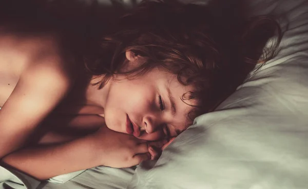 Sovande barn ligger i sängen med slutna ögon. — Stockfoto