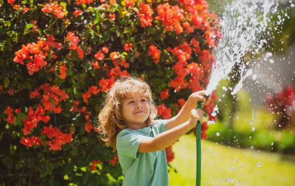 I bambini giocano con tubo da giardino dell'acqua in cortile. Divertimento estivo per bambini all'aperto. Ragazzino che gioca con il tubo dell'acqua in giardino. Gioco di partito per bambini. Attività salutare per la calda giornata di sole. — Foto Stock