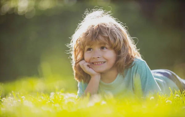 Portrait of little boy laying on grass in summer nature park. — Stock Photo, Image