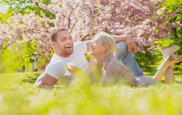 Mutlu bahar çifti eğleniyor. Güzel gülümseyen genç aşıklar çiçek bahçesinin tadını çıkarıyorlar.. — Stok fotoğraf