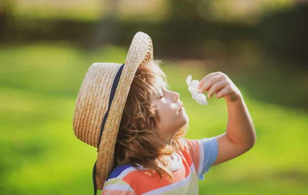 Hasır şapkalı şirin bir çocuğun Plumeria çiçeği kokan portresi. Çocukluk ve ebeveynlik kavramı. Yaz tatili. — Stok fotoğraf