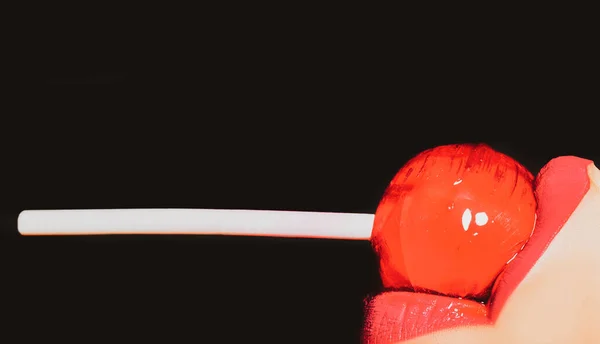 Sug slickklubba. Slicka godis. Lollipop i sexig sensuell mout isolerad på svart bakgrund. Glamour vackra röda läppar äter svettningar lolly pop. — Stockfoto