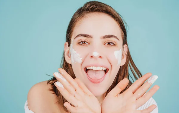 Funny beautiful young woman with clean fresh skin applying face cream. — Stock Photo, Image