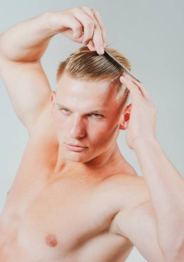 Erkek kuaför. Taraklı adam. Güzellik, bakım ve insan konsepti. Saçlarını tarayan yakışıklı bir erkek. İzole edilmiş.