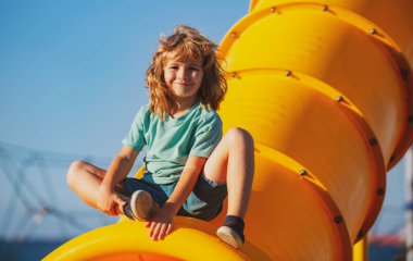 Neşeli çocuk dışarıda oyun alanında eğleniyor. Komik çocuk suratı.