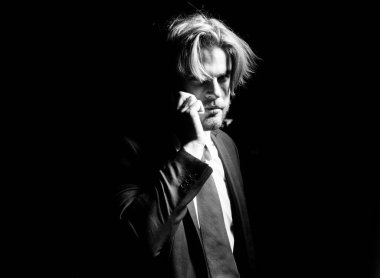 İş adamı karanlıktan arıyor. Adamın akıllı telefonu var. Karanlık bir arka planda bir iş adamının portresi.